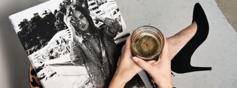 Comment garder un média d’avance ? Une femme lit son magazine en tenant un café noir et porte des talons noirs