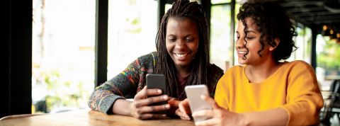 Pourquoi les applis financières portent-elles un prénom ? Deux femmes en train de s'échanger de l 'argent via une application smartphone.