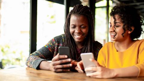 Deux femmes en train de s'échanger de l 'argent via une application smartphone.