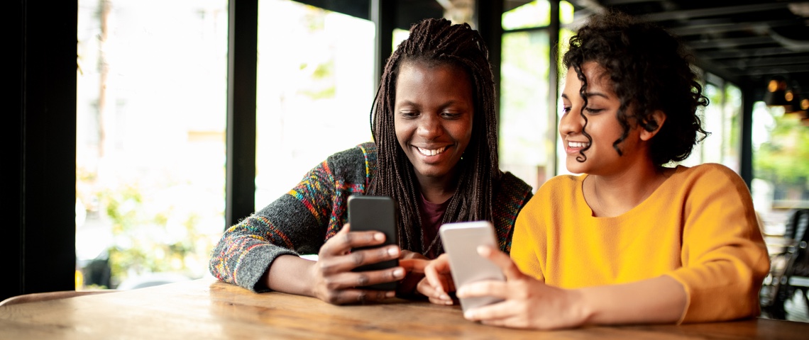 Pourquoi les applis financières portent-elles un prénom ? Deux femmes en train de s'échanger de l 'argent via une application smartphone.
