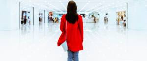 Une femme avec un manteau rouge de dos dans un centre commercial