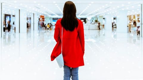 Une femme avec un manteau rouge de dos dans un centre commercial