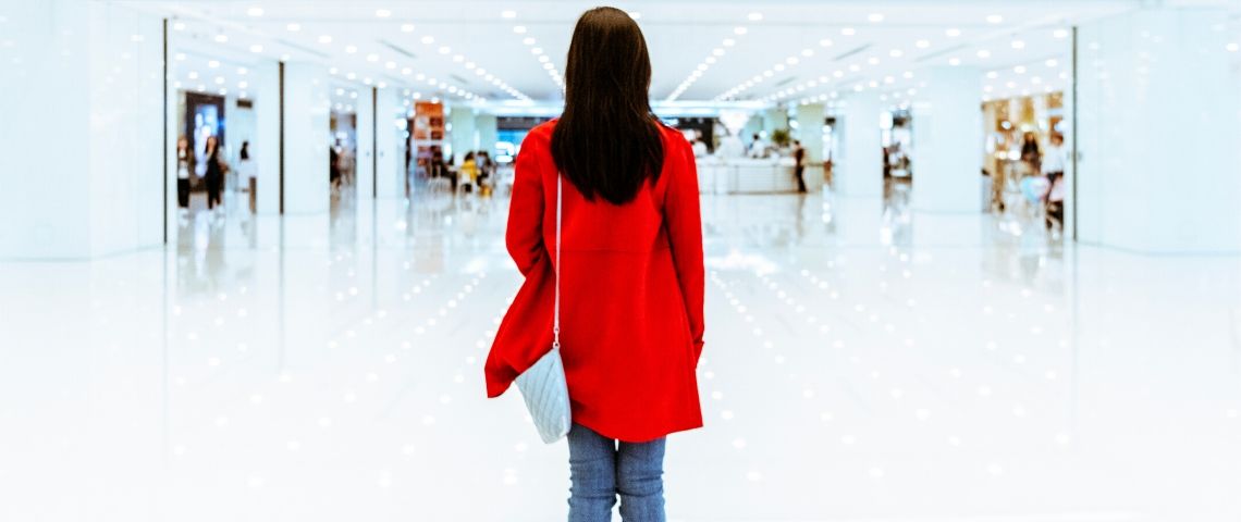 5 initiatives pour une meilleure inclusion des personnes autistes Une femme avec un manteau rouge de dos dans un centre commercial