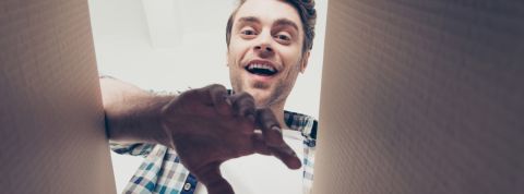 Wish : pourquoi ce bazar du web, loin de la consommation responsable, cartonne Homme vue contre-plongée en train d'ouvrir un colis en carton.