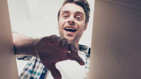 Homme vue contre-plongée en train d'ouvrir un colis en carton.