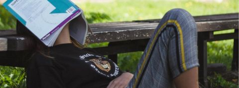 On a oublié comment s'ennuyer Une jeune femme assise en train de dormir avec un livre sur la tête