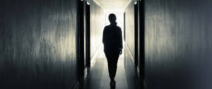 uune femme de dos dans un couloir sombre