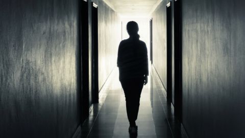 uune femme de dos dans un couloir sombre