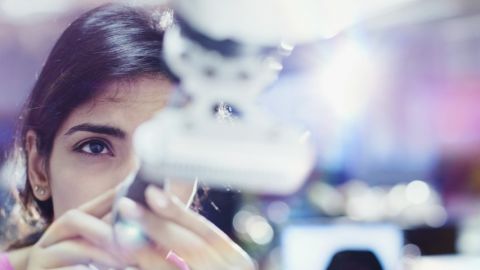 Femme ingénieure en train de travailler sur un bras robotique.