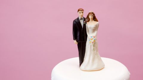 Deux figurines de mariés sur un gâteau de mariage.