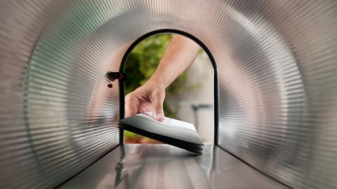 une main rentre dans une boite au lettres pour y déposer... des lettres