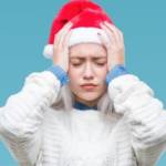 Une jeune femme avec un bonnet de père Noël qui a la migraine
