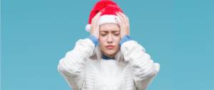 Une jeune femme avec un bonnet de père Noël qui a la migraine