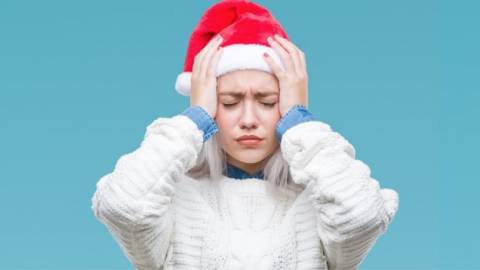 Une jeune femme avec un bonnet de père Noël qui a la migraine