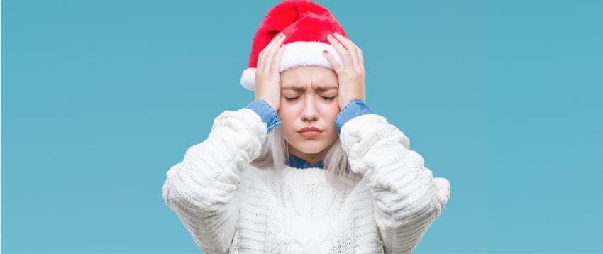 Les jeunes actifs ne veulent plus fêter Noël au bureau Une jeune femme avec un bonnet de père Noël qui a la migraine