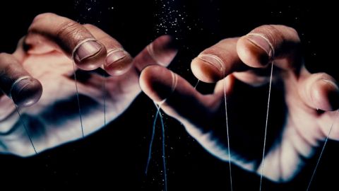 Des mains d'hommes en train de manipuler des ficelles de pantin