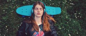 Une jeune femme qui écoutent de la musique avec un casque bleu sur les oreilles