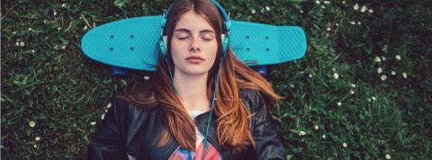 Quelles sont les meilleures musiques pour se relaxer ? Une jeune femme qui écoutent de la musique avec un casque bleu sur les oreilles
