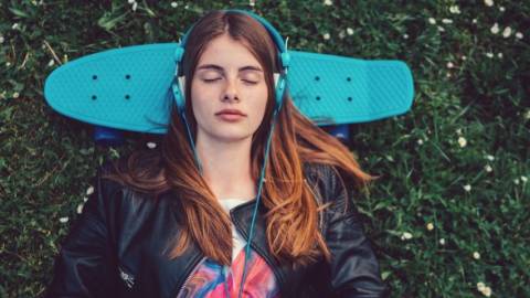 Une jeune femme qui écoutent de la musique avec un casque bleu sur les oreilles