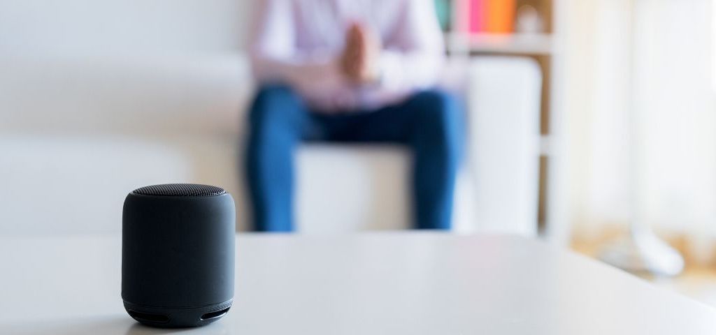Ces assistants vocaux qui en savent plus sur vous que… vous Homme assis sur son canapé et parle à son assistant vocal