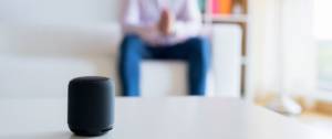 Homme assis sur son canapé et parle à son assistant vocal
