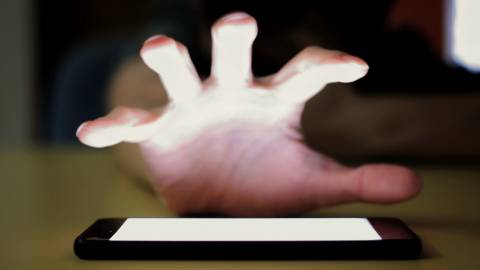 Une main cherche à s'emparer de son smartphone