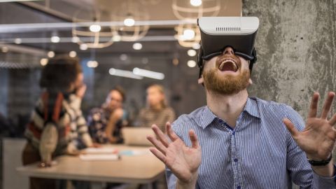 Salarié d'une start-up portant un casque de réalité virtuelle avec un air ébahi