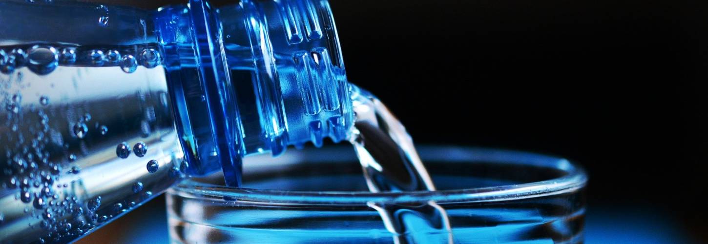 Les marques Eaux de Danone s'engagent à réduire leurs émissions carbone et lutter contre le changement climatique Eau versée dans un verre