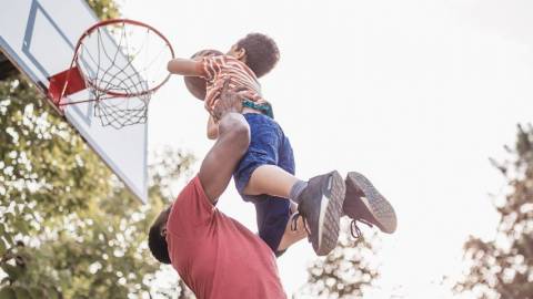 Papa porte son petit garçon qui joue au basket