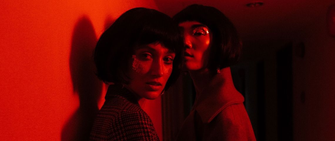 Comment les marques mettent à profit la génération d'UGC ? Deux influenceuses se font prendre en photos dans une lumière rouge