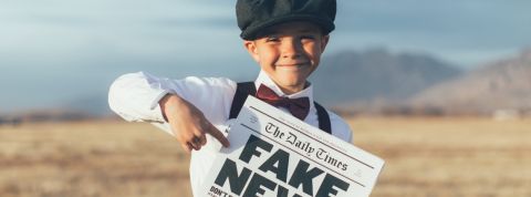 Les enfants du Gorafi confondent satire et fake news un enfant dans un champs qui tient un journal avec écrit fake news dessus
