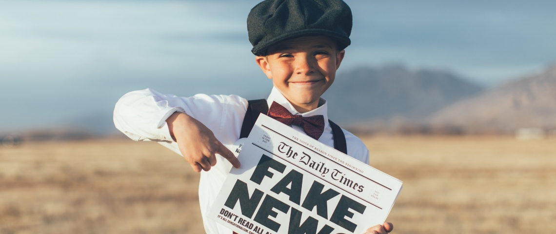 Les enfants du Gorafi confondent satire et fake news un enfant dans un champs qui tient un journal avec écrit fake news dessus