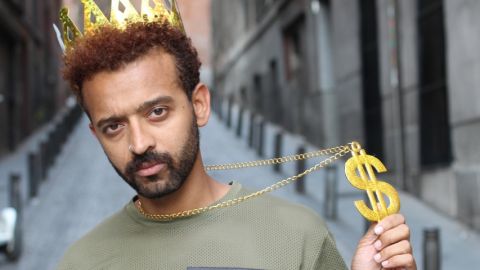 un influenceur dans la rue avec une couronne dorée qui exhibe fiérement un pendantif en forme de dollars