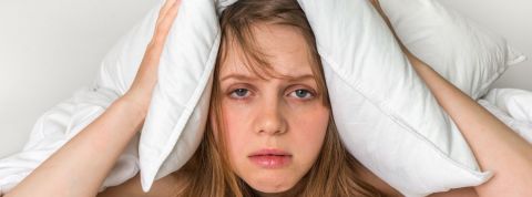 Penser moins pour dormir plus Une femme insomniaque qui tient sa tête entre deux oreillers