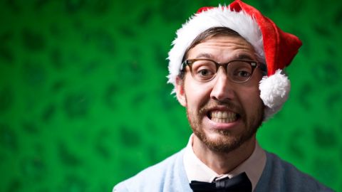 Un monsieur l'air gêné avec un chapeau de père noel sur la tête.