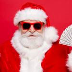 Homme déguisé en père Noël tient une carte bancaire et de l'argent.