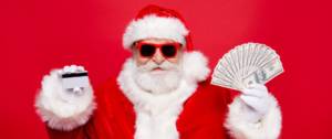 Homme déguisé en père Noël tient une carte bancaire et de l'argent.