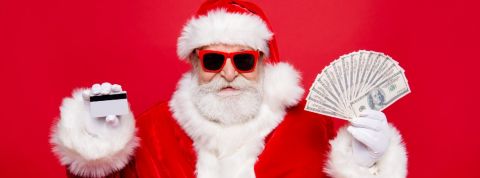 Pourquoi Noël est un eldorado pour les cyberciminels Homme déguisé en père Noël tient une carte bancaire et de l'argent.