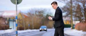 Homme traversant la route en regardant son smartphone