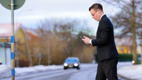Homme traversant la route en regardant son smartphone