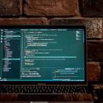 Un ordinateur posé sur un bureau et ouvert sur des lignes de code.