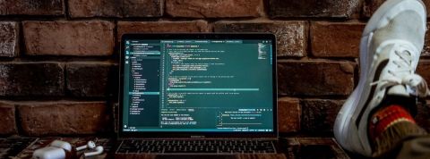 Elon musk récompense ses hackers. Un ordinateur posé sur un bureau et ouvert sur des lignes de code.