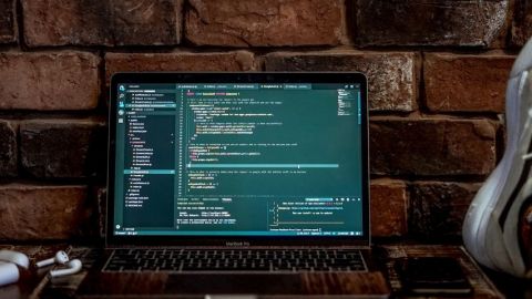 Un ordinateur posé sur un bureau et ouvert sur des lignes de code.