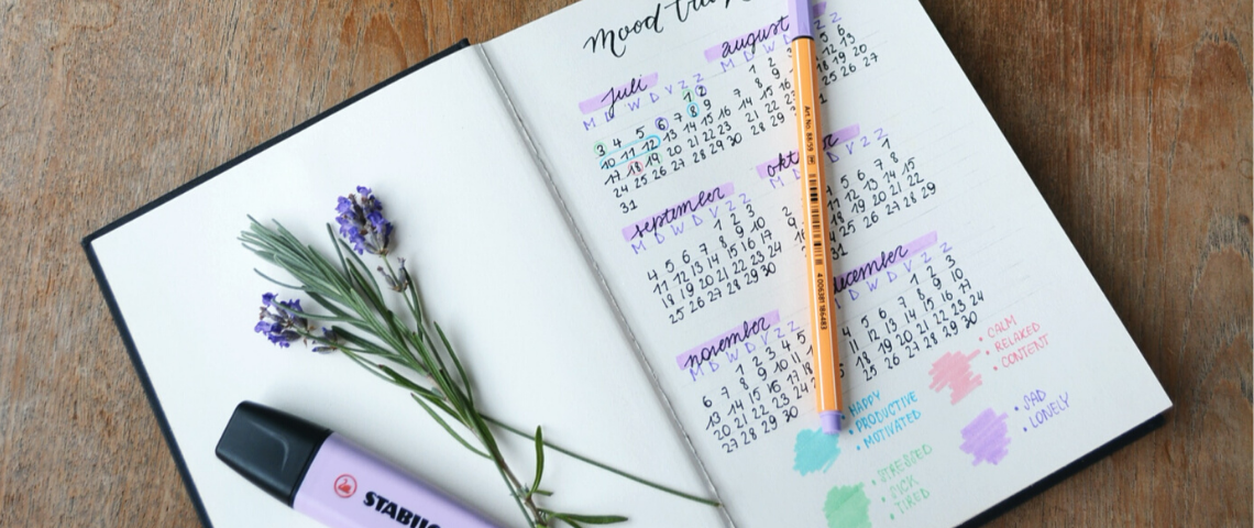 4 applications pour tenir ses résolutions. un carnet aux pages blanches ouvertes sur une table de bois avec un stabilisateur violet