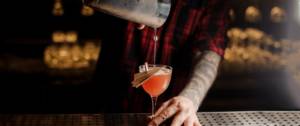 Un barman qui verse un cocktail dans un verre