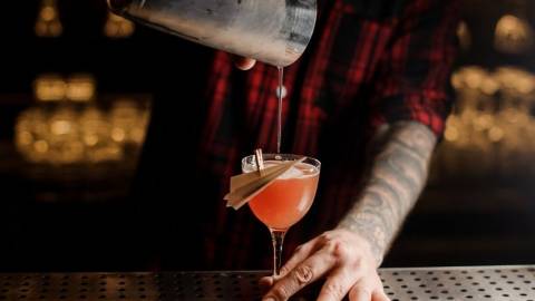Un barman qui verse un cocktail dans un verre