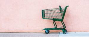 Un chariot de supermarché vert abandonné devant un mur rose