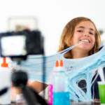 une jeune fille joue avec du slime face caméra.