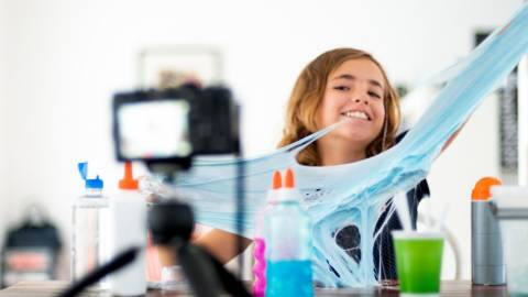 une jeune fille joue avec du slime face caméra.
