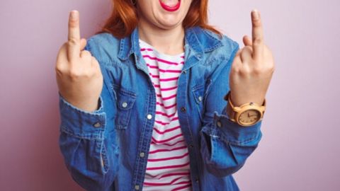 Femme portant une veste en jean fait deux doigts d'honneur face à la caméra